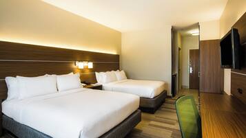 A hotel room with two beds, a desk, a chair, a TV, and a wooden headboard.