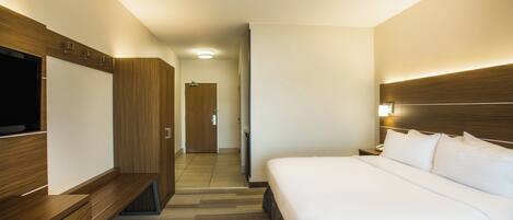 A hotel room with a bed, a TV, a desk, and a wardrobe.