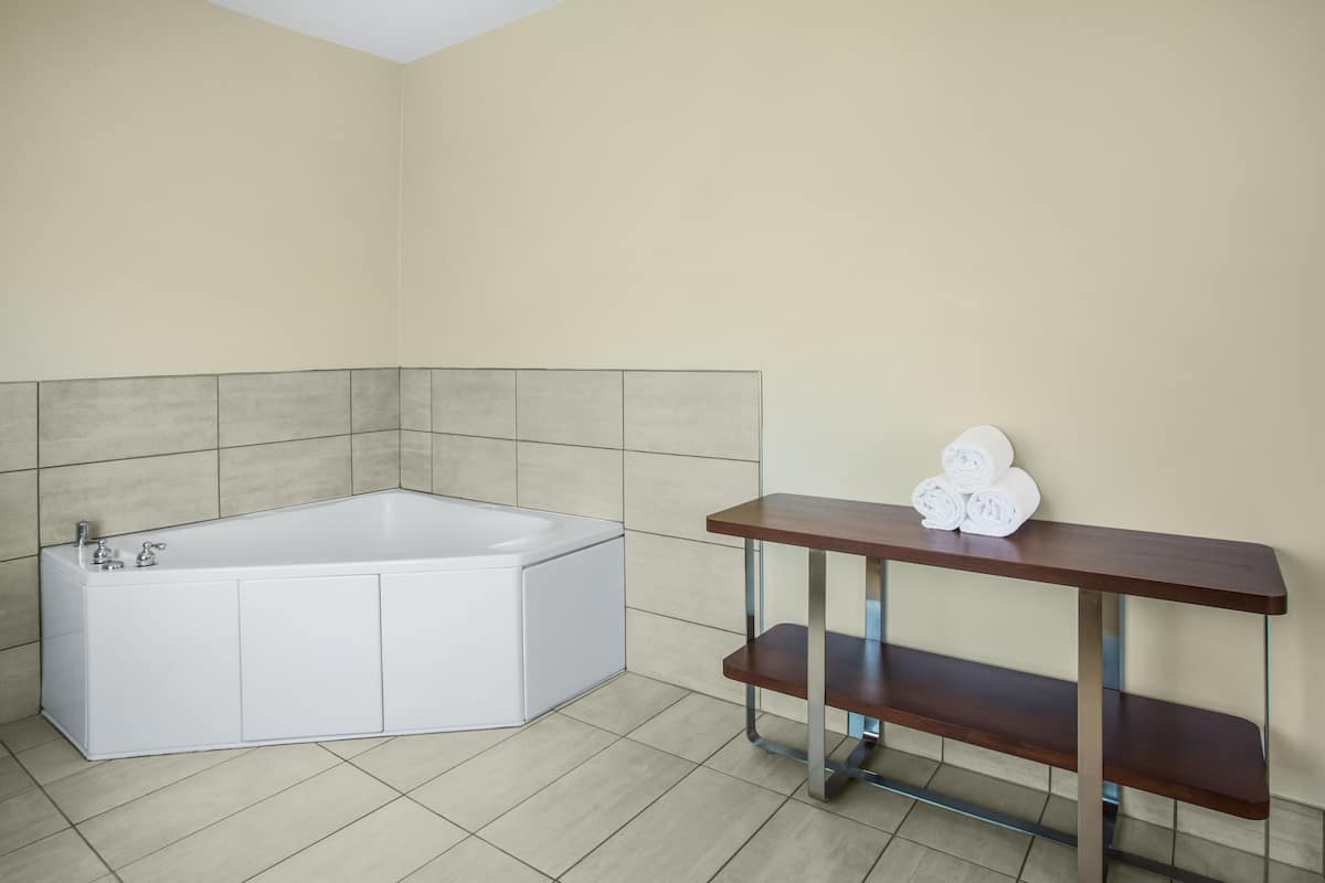 A modern bathroom with a freestanding bathtub, a wooden vanity with a towel rack, and tiled walls.