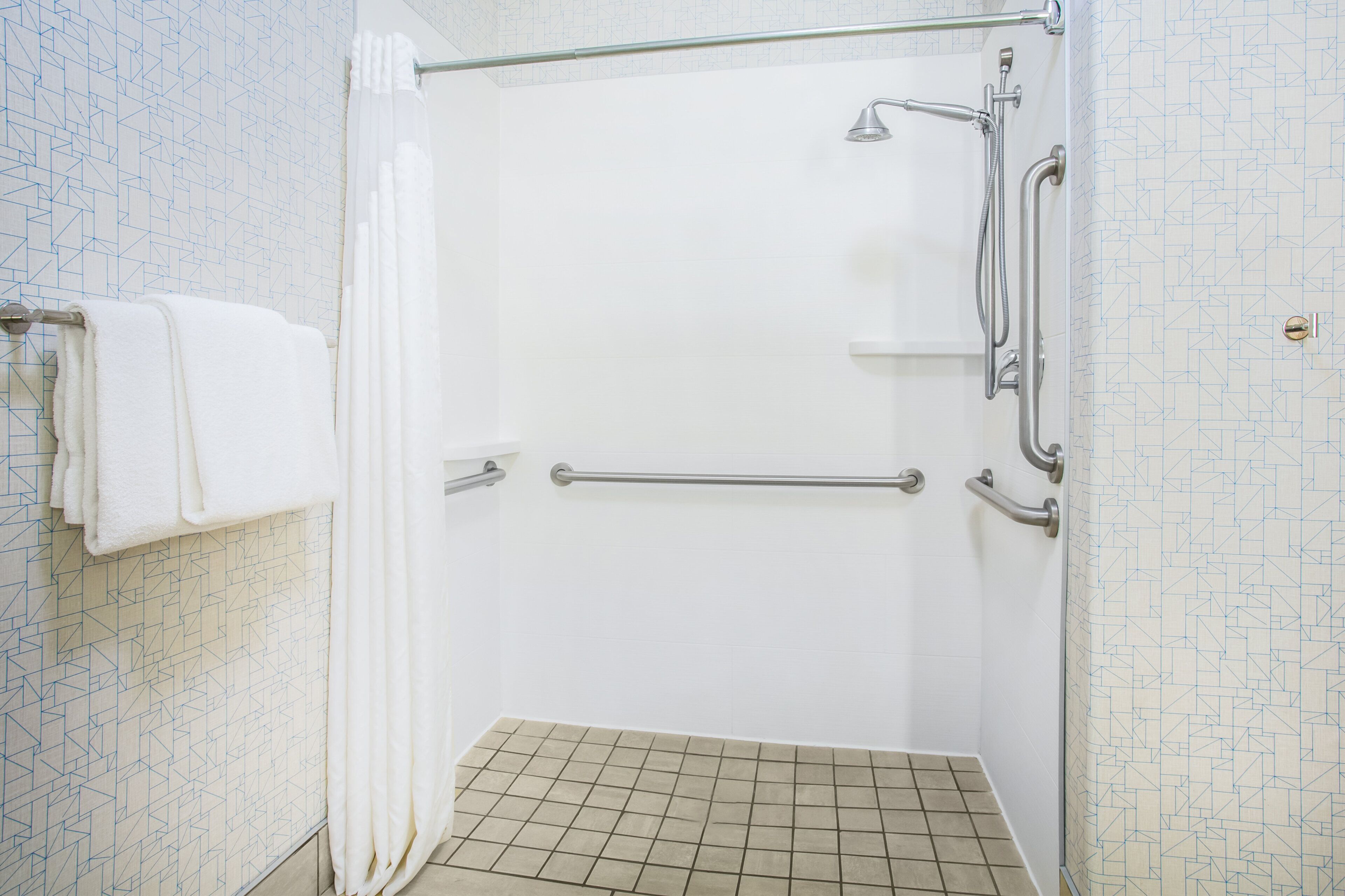Une salle de bain équipée d’une douche, de barres d’appui et d’un porte-serviettes.
