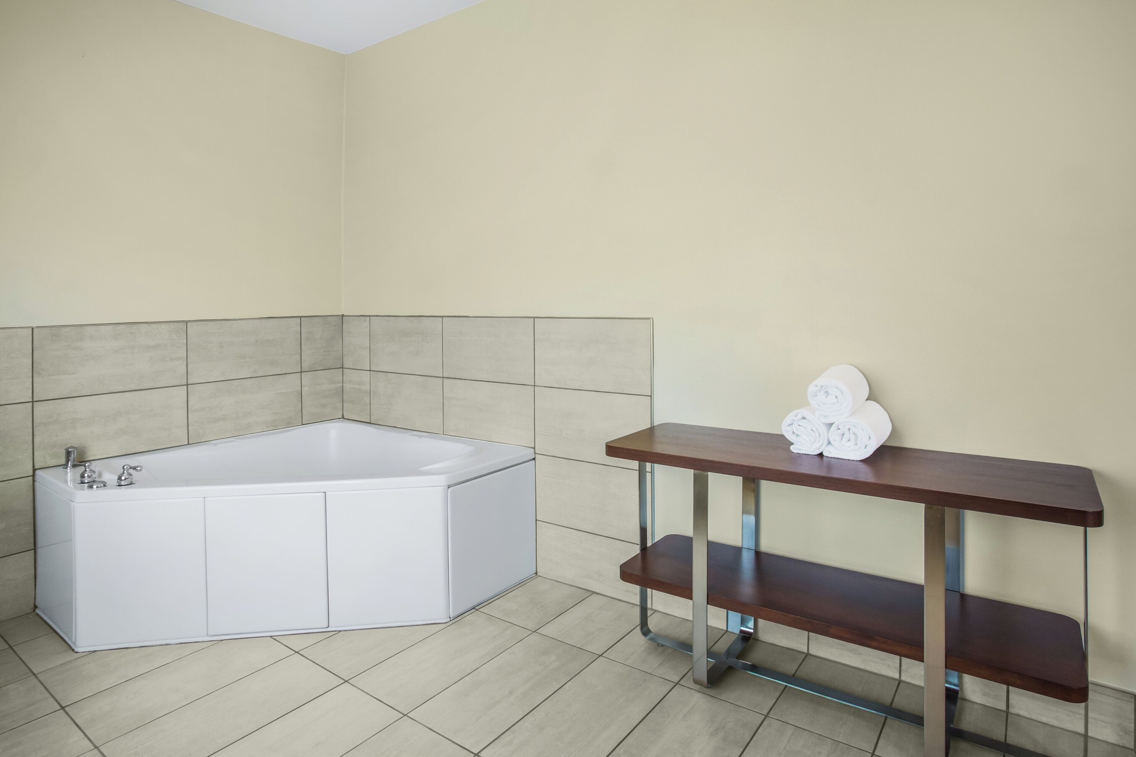 Une salle de bain avec une baignoire blanche, un banc en bois et un porte-serviettes avec des serviettes.
