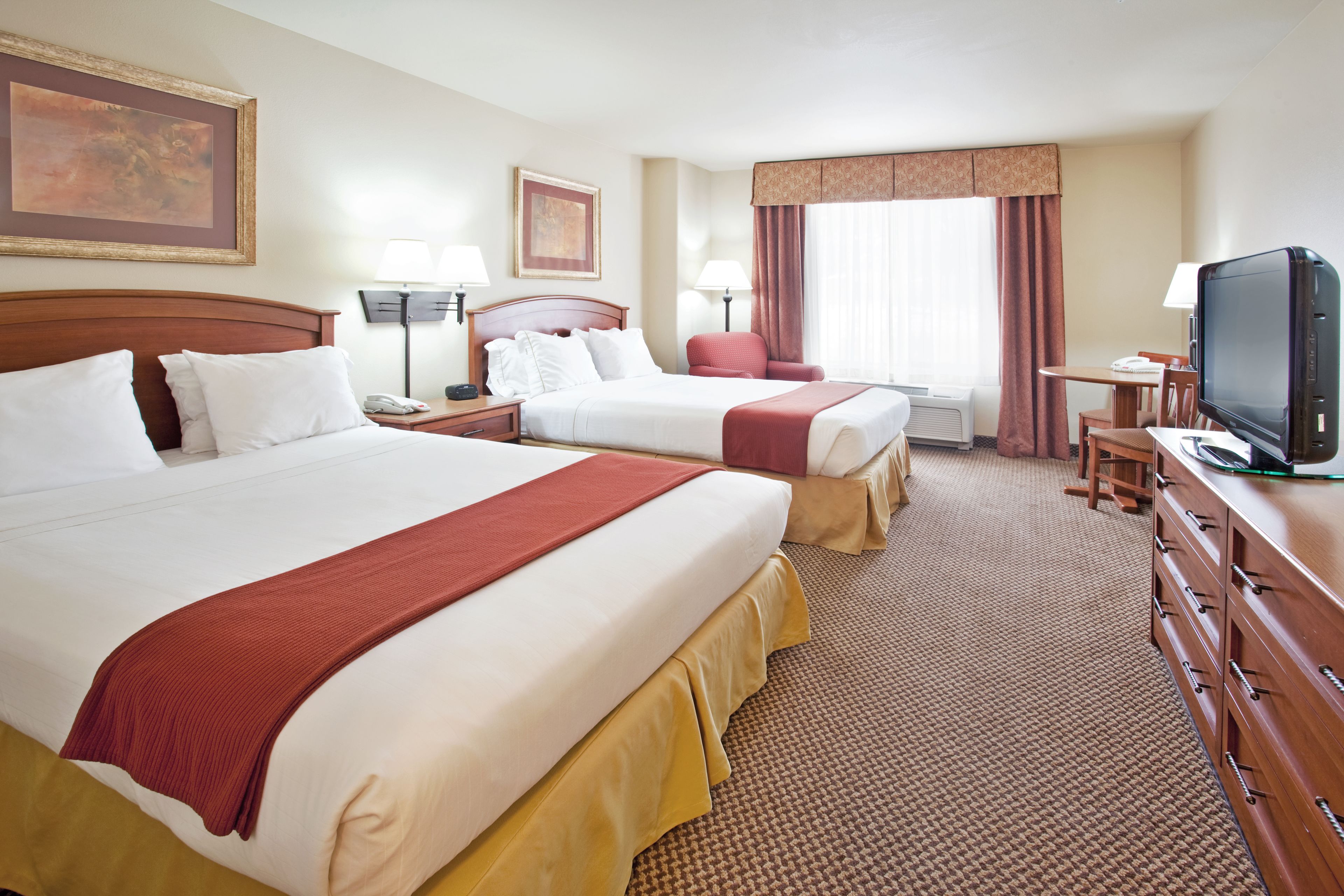 A hotel room with two beds, a TV, a desk, and a chair.
