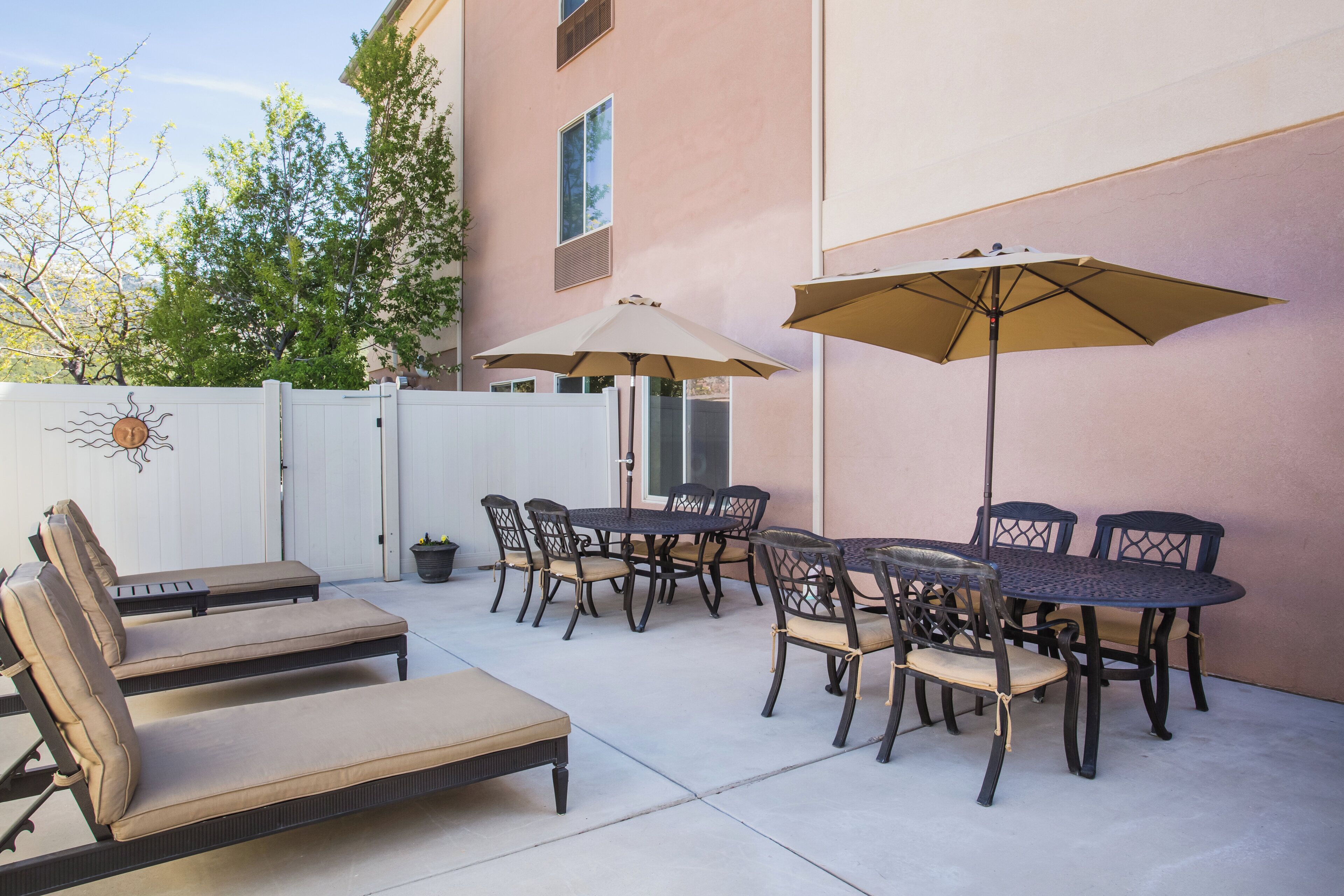 An outdoor patio with a round table, chairs, and two sun loungers.