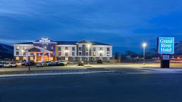 Ein Hotel mit einem Schild, das "Grand River Hotel" zeigt, und einem Parkplatz mit mehreren Autos.