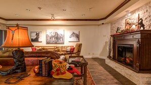 Una sala de estar acogedora con chimenea, sofá de cuero y obras de arte con motivos ecuestres.