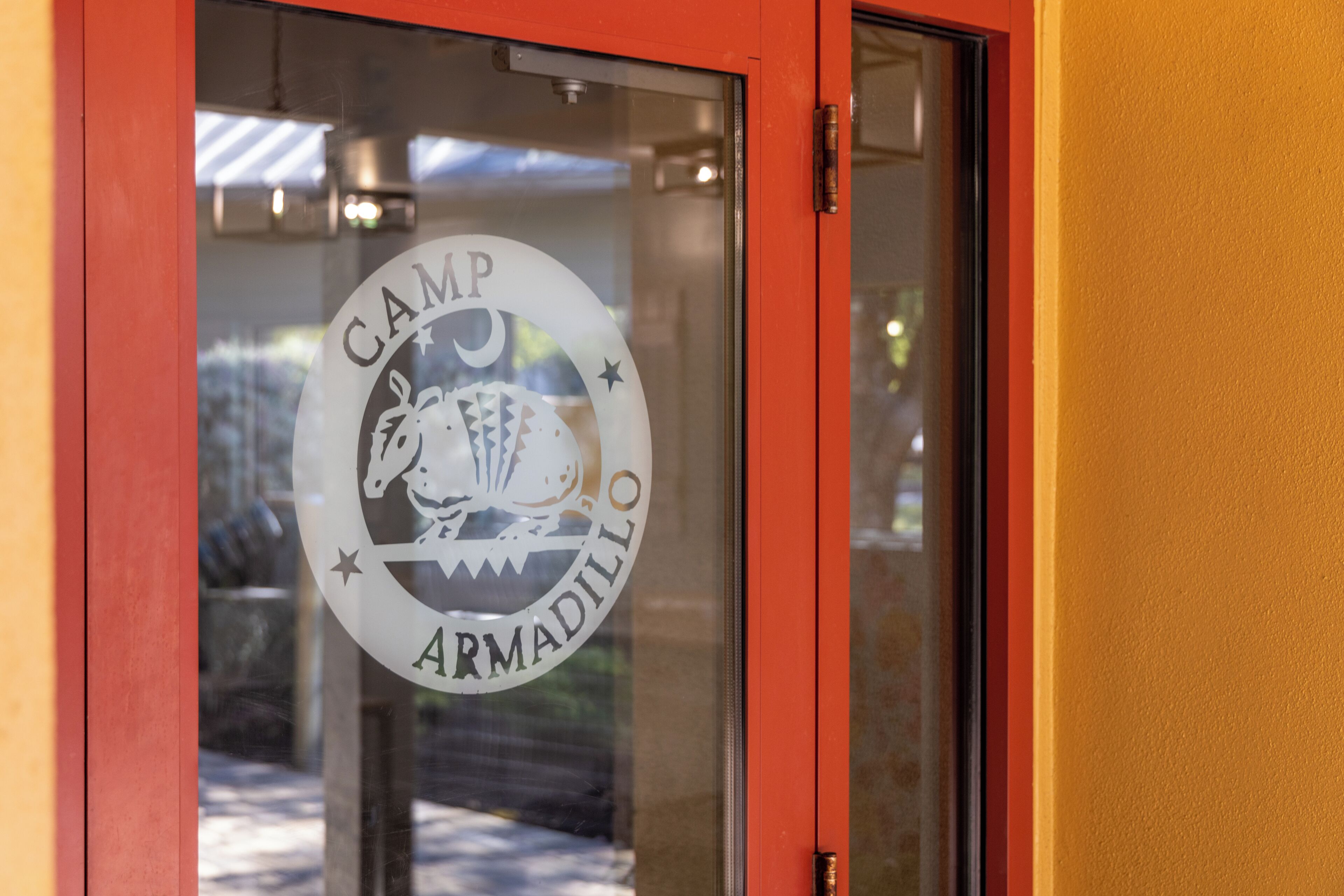 A glass door with a logo that reads "CAMP ARMADILLO".
