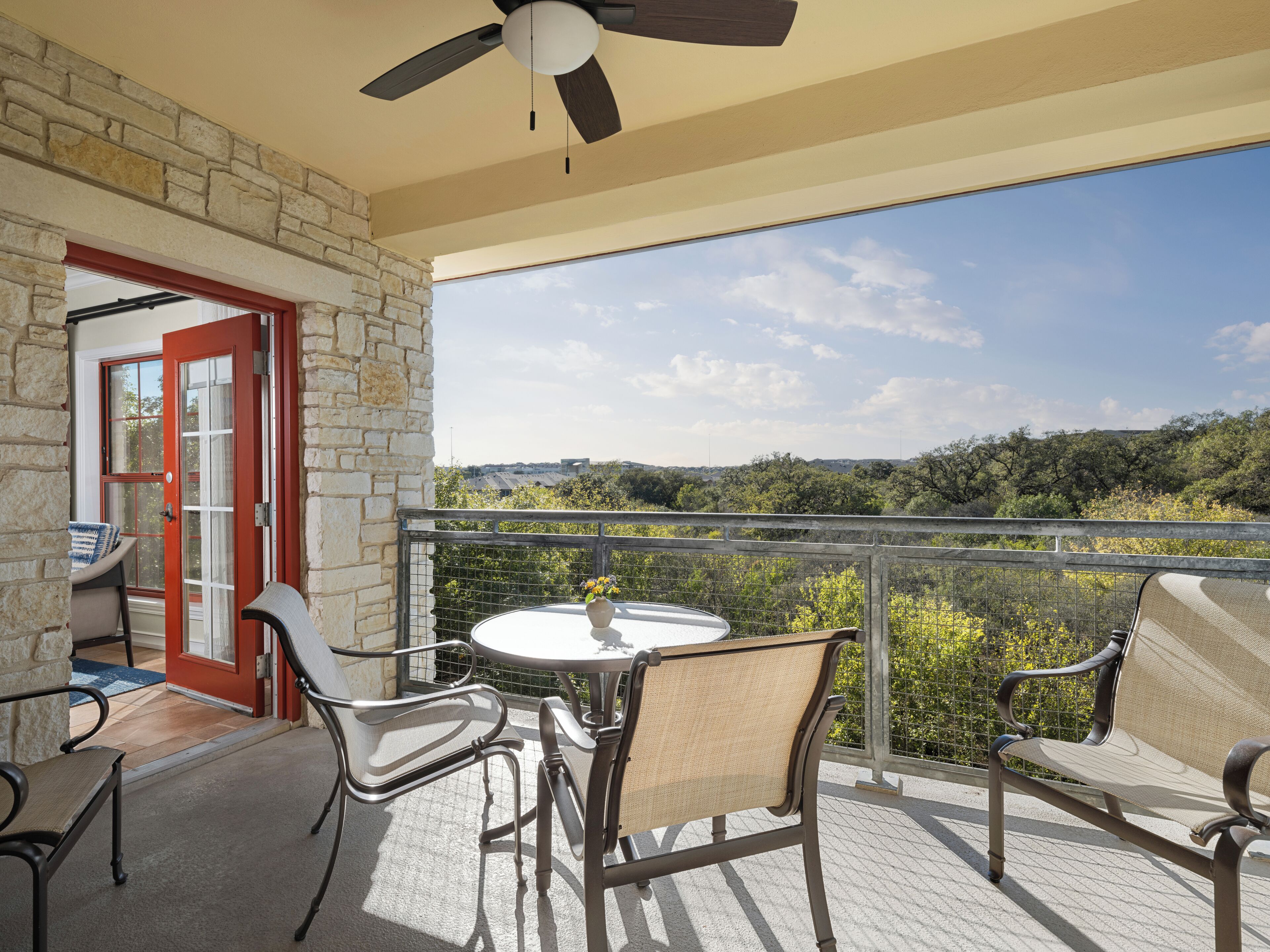 A balcony with a table and chairs, a ceiling fan, and a view of the landscape.