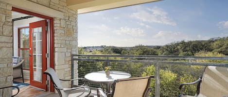 A balcony with a table and chairs, a ceiling fan, and a view of the landscape.