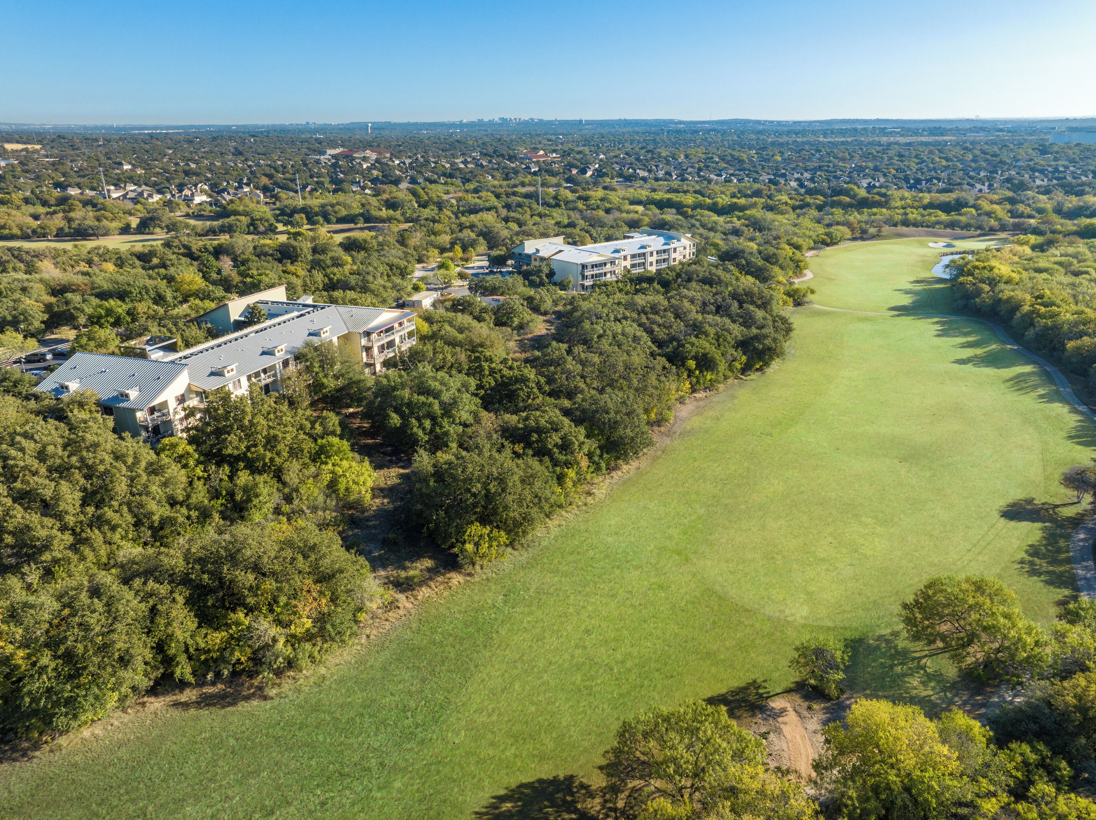 Vue aérienne d’un terrain de golf avec un club-house et des immeubles résidentiels.