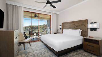 Habitación de hotel con una cama grande, un escritorio, una silla, un ventilador de techo, una mesita de noche y vistas al exterior.