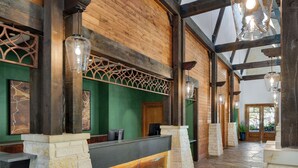 A reception area with a wooden reception desk, stone pillars, and a green wall. - Hyatt Vacation Club at Wild Oak Ranch, San Antonio (San Antonio)