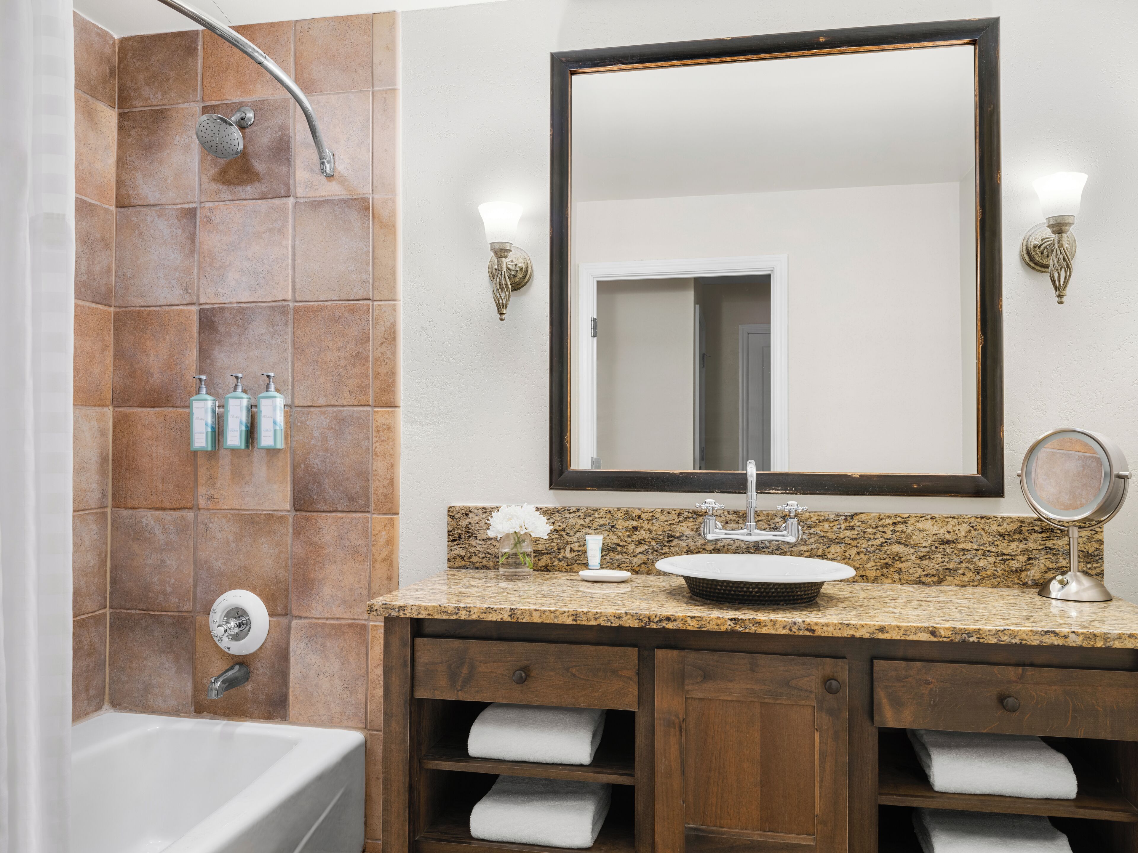 Ein Badezimmer mit Dusche, Waschbecken, Spiegel und Holzschränken.