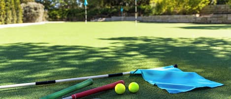 A green artificial turf with golf clubs and golf balls.