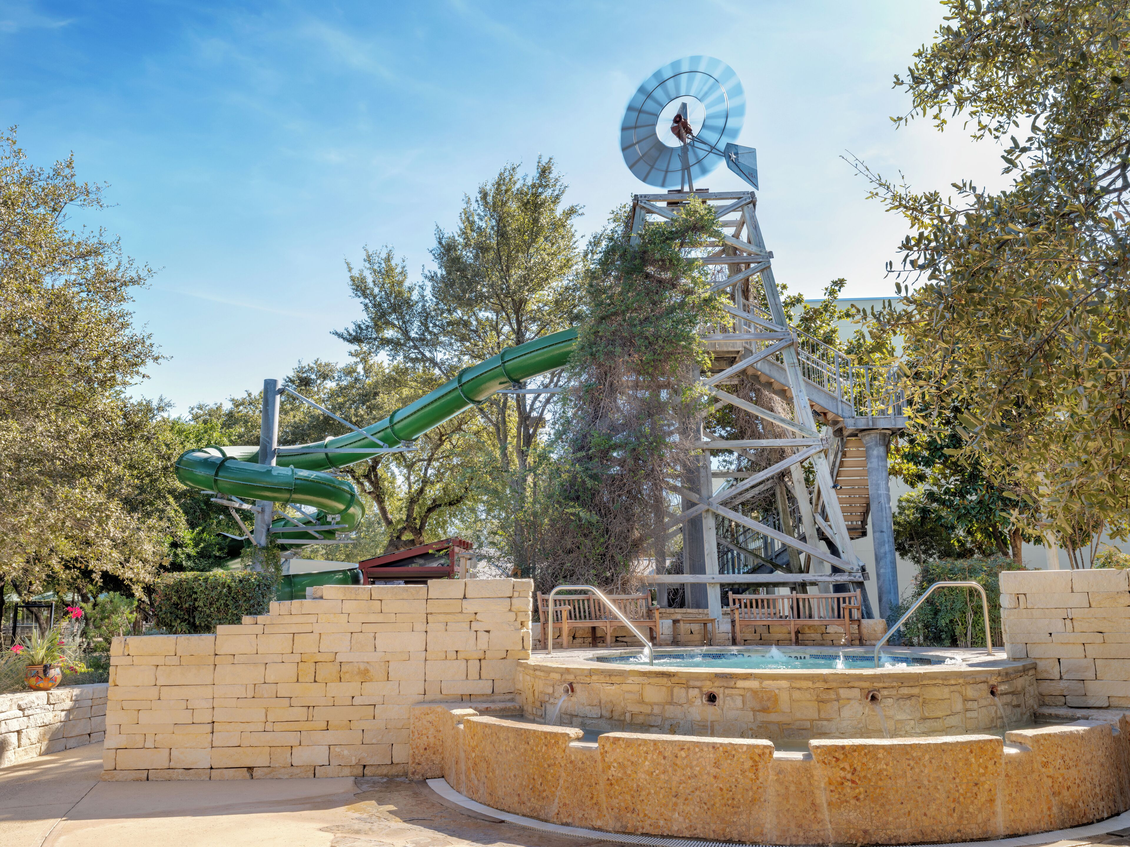 Parque acuático con tobogán de agua, piscina y estructura con forma de molino.