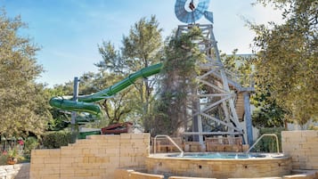 Un parc aquatique comprenant un toboggan aquatique, une piscine et une structure en forme de moulin à vent.