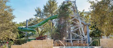 Parque acuático con tobogán de agua, piscina y estructura con forma de molino.