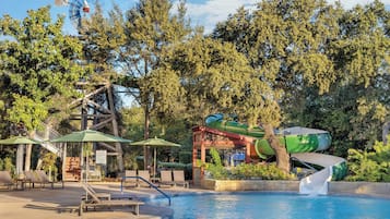Relax by the serene pool surrounded by lush greenery and trees, featuring a well-maintained pool, lounge chairs, and a unique windmill structure.