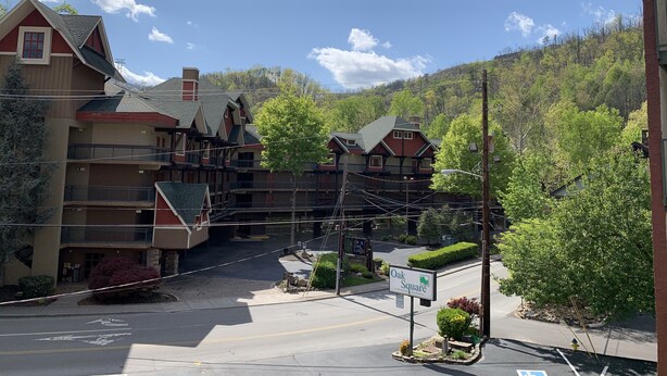 A multi-story building with a red and beige facade, a green roof, and a sign indicating 'Oak Square'. - Oak Square Rentals (Gatlinburg)