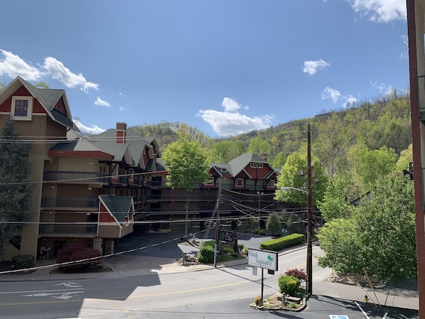 A multi-story building with a red and beige facade, a green roof, and a sign indicating 'Oak Square'. - Oak Square Rentals (Gatlinburg)