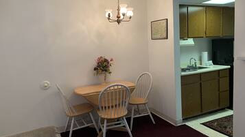 A dining area with a wooden table and four chairs, a vase of flowers, and a chandelier.