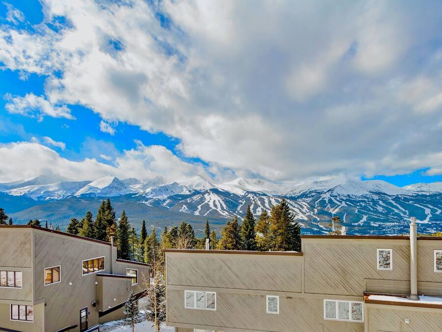 A modern building with multiple windows and a view of snow-capped mountains in the background.