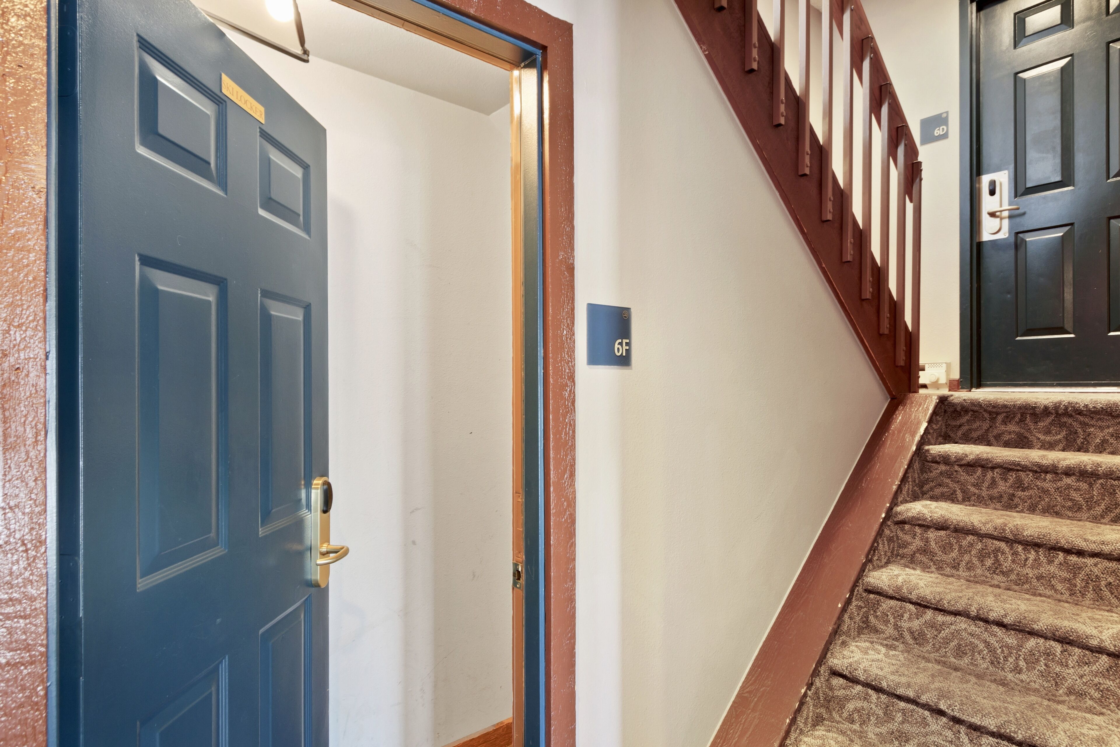 A staircase with a wooden handrail and a blue door with a brass handle.