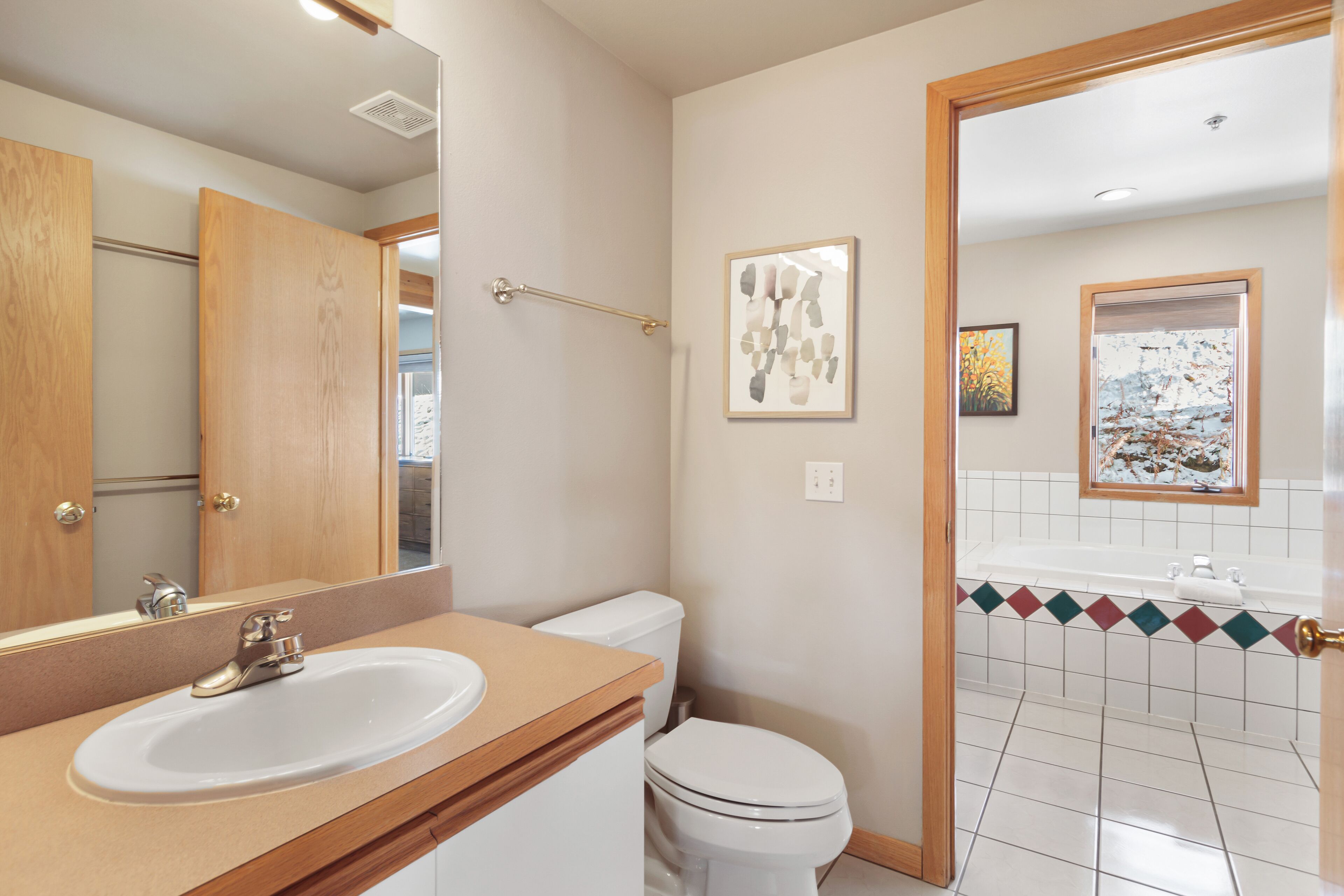 A bathroom with a wooden vanity, a white sink, a toilet, and a shower area.