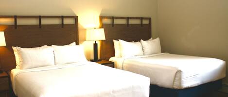Two single beds with wooden headboards, a nightstand with a lamp, and a wall-mounted light fixture.