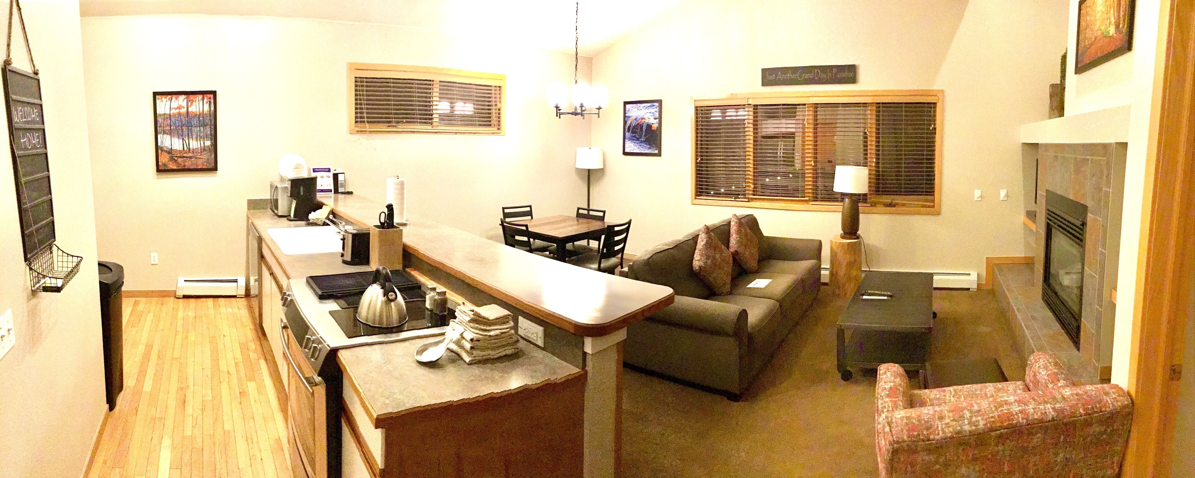A compact living space with a kitchenette, a sofa, a small table, and a fireplace.
