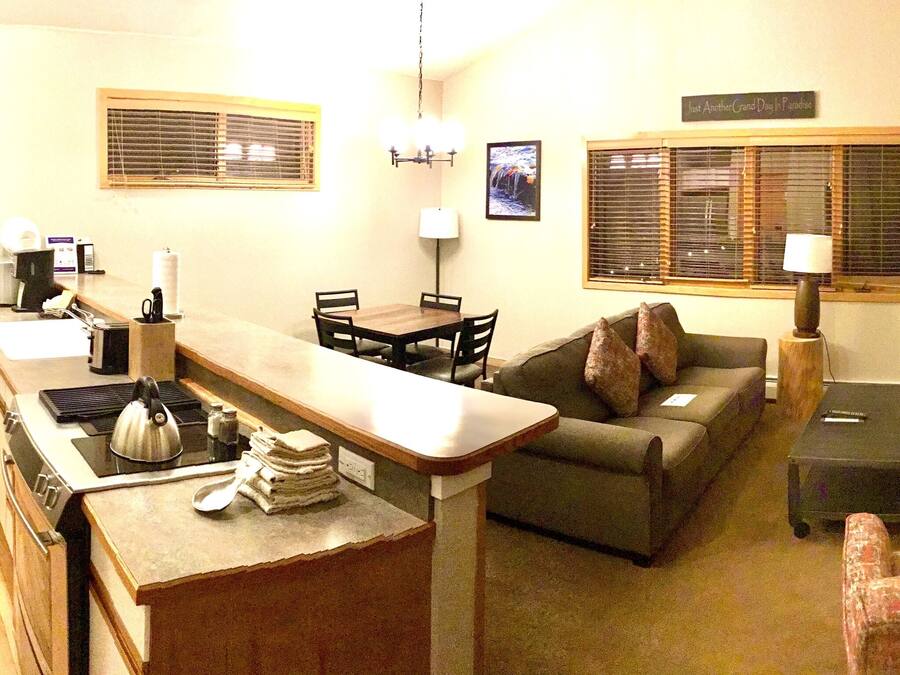 A compact living space with a kitchenette, a sofa, a small table, and a fireplace.