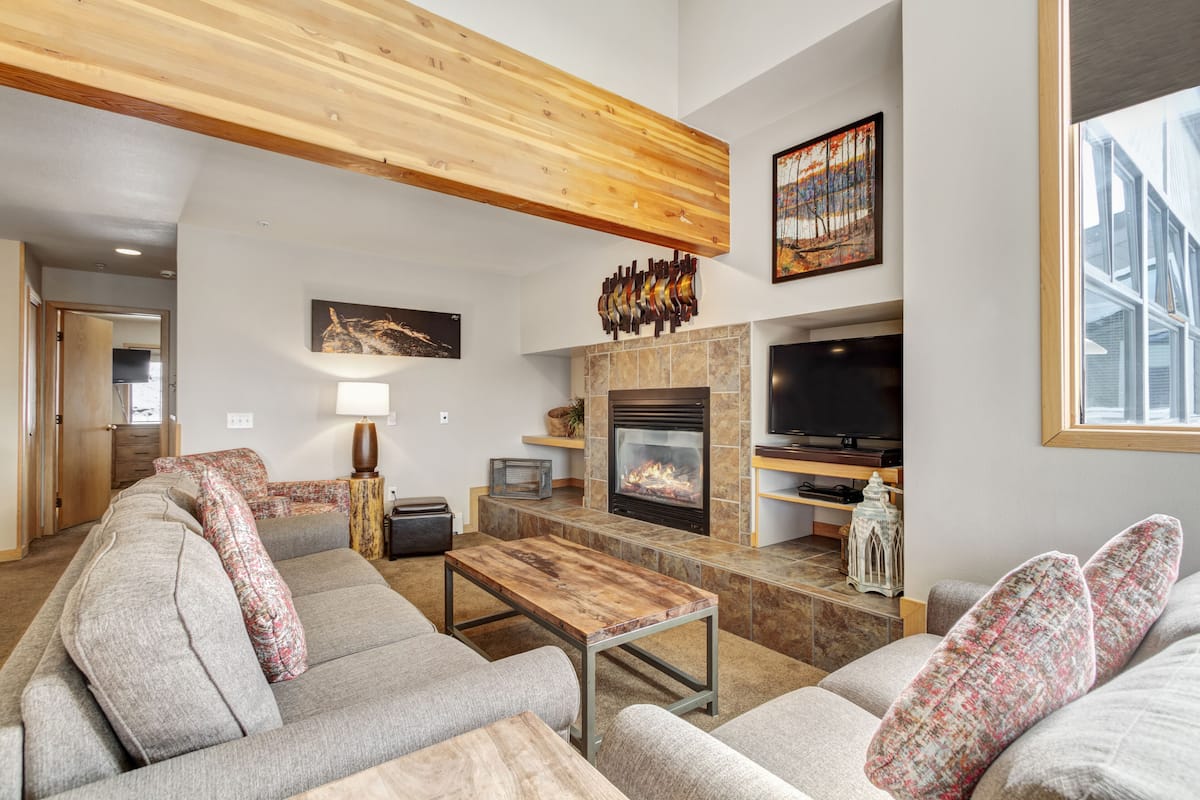 A modern living room with a fireplace, sofas, a coffee table, and a television.