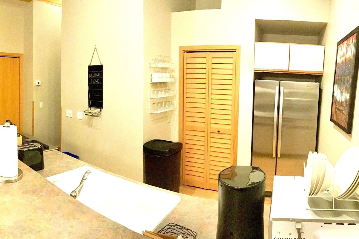A compact living space with a sofa, dining table, and kitchen area including a refrigerator and microwave.