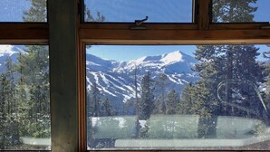 Une vue dégagée sur un paysage montagneux, visible à travers une fenêtre, avec une piscine au premier plan.