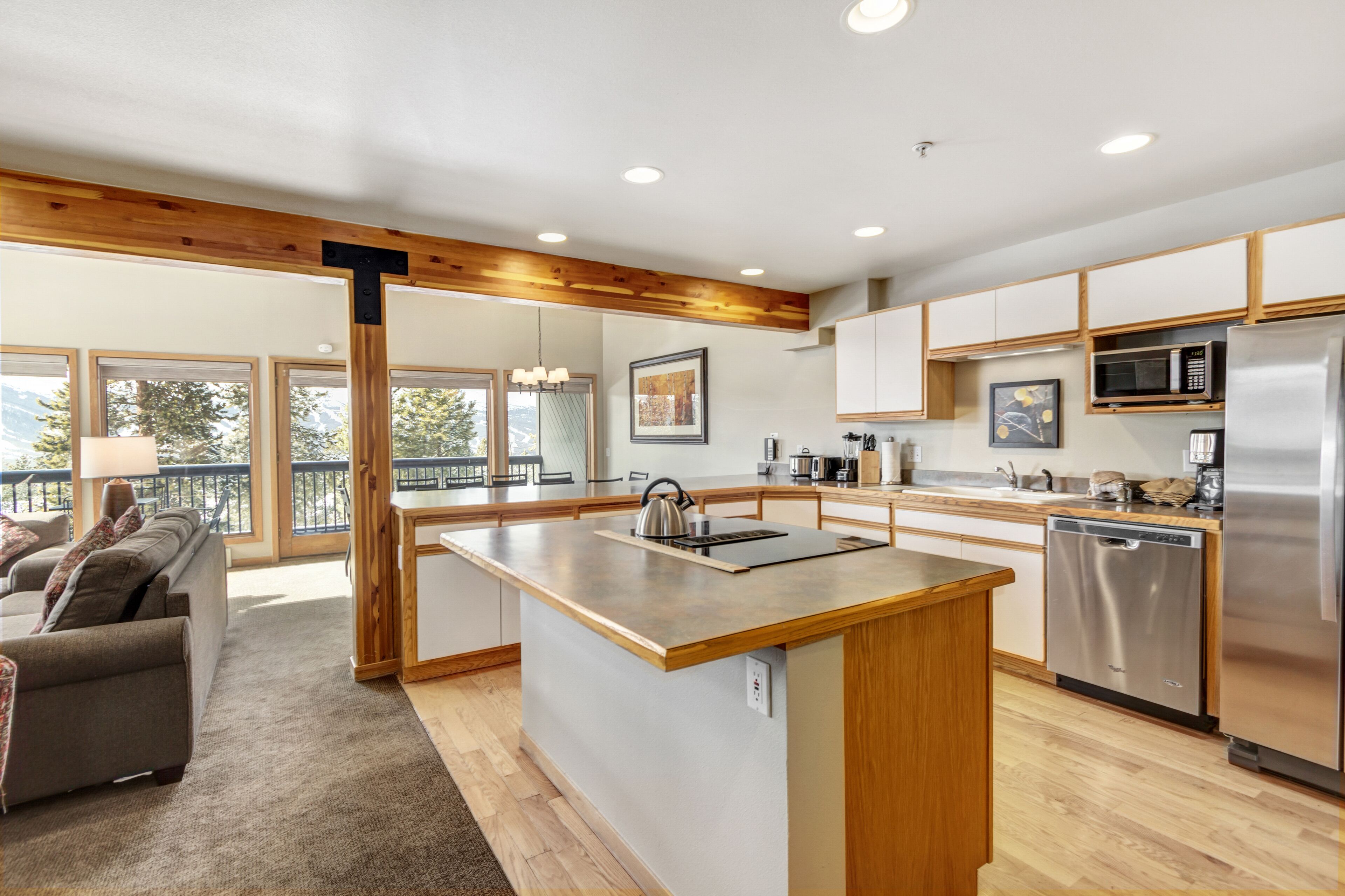 A modern kitchen with a central island, stainless steel appliances, and wooden cabinetry.