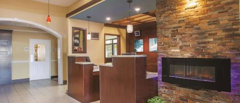 A reception area with a stone wall, a flat-screen TV, and a reception desk.