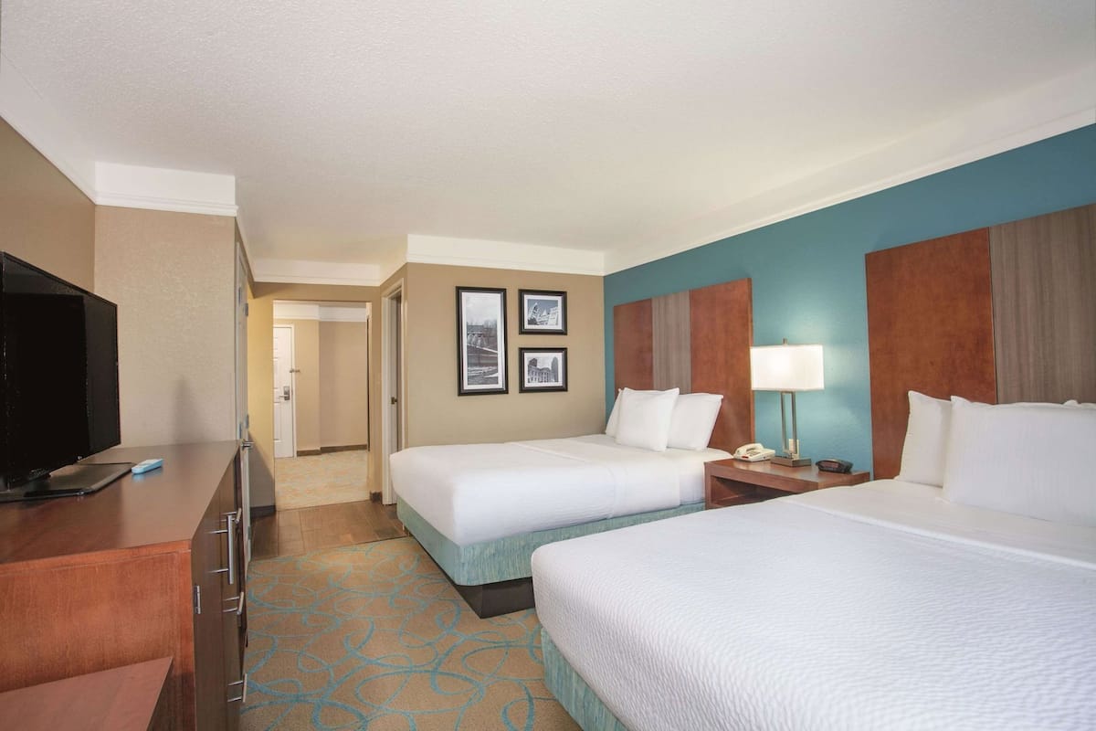 A hotel room with two beds, a TV, a desk, and a phone.