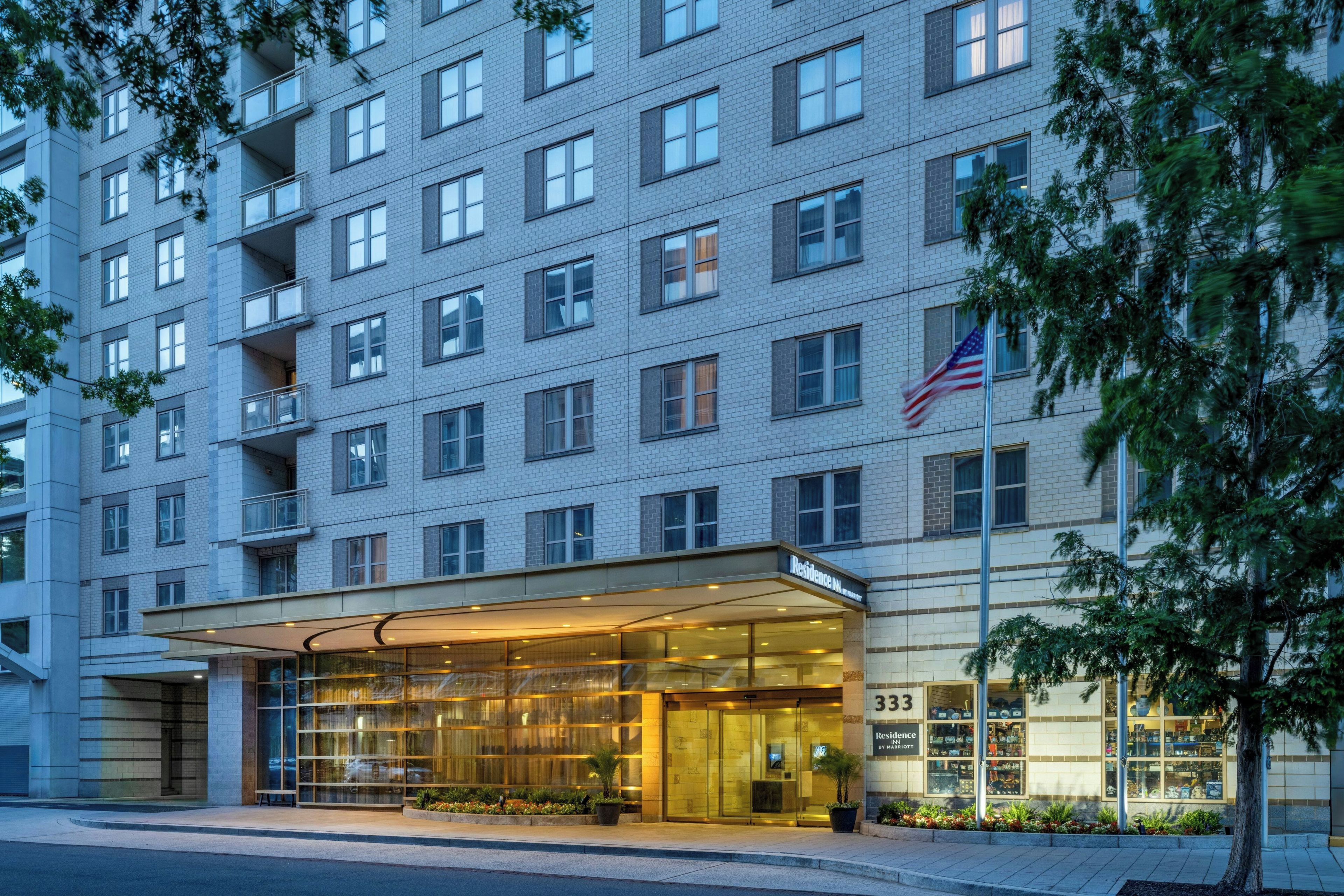 A multi-story hotel with a glass entrance and a flag on the corner.