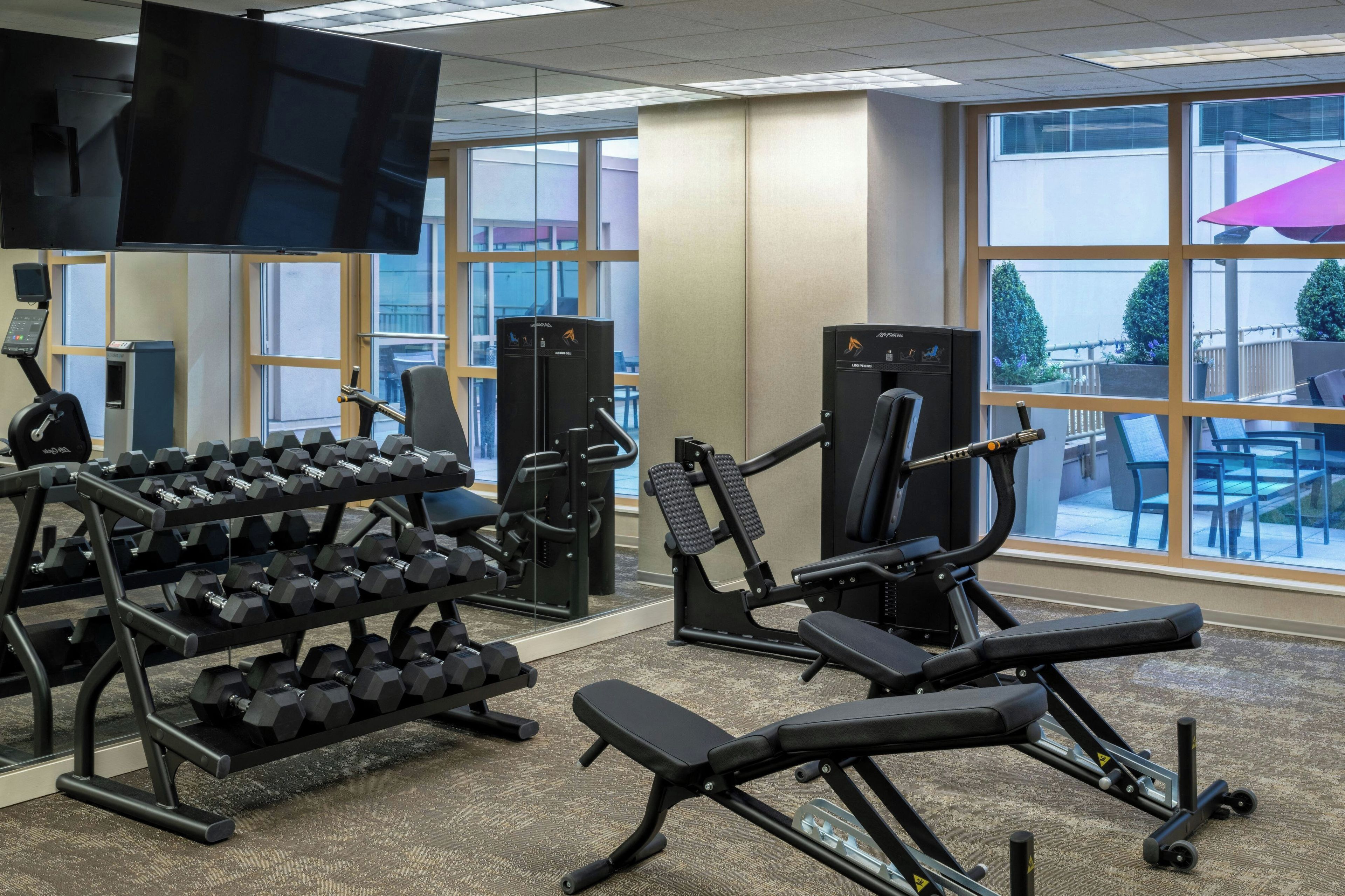 A gym with various exercise equipment, including dumbbells, a bench, and weight machines.