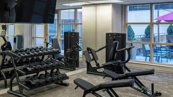 A gym with various exercise equipment, including dumbbells, a bench, and weight machines.