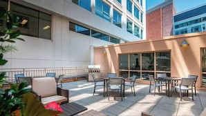 An outdoor patio with seating and a grill area, surrounded by modern buildings. - Residence Inn by Marriott Washington, DC National Mall (Washington)