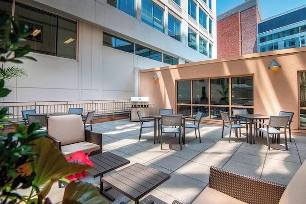 An outdoor patio with seating and a grill area, surrounded by modern buildings. - Residence Inn by Marriott Washington, DC National Mall (Washington)