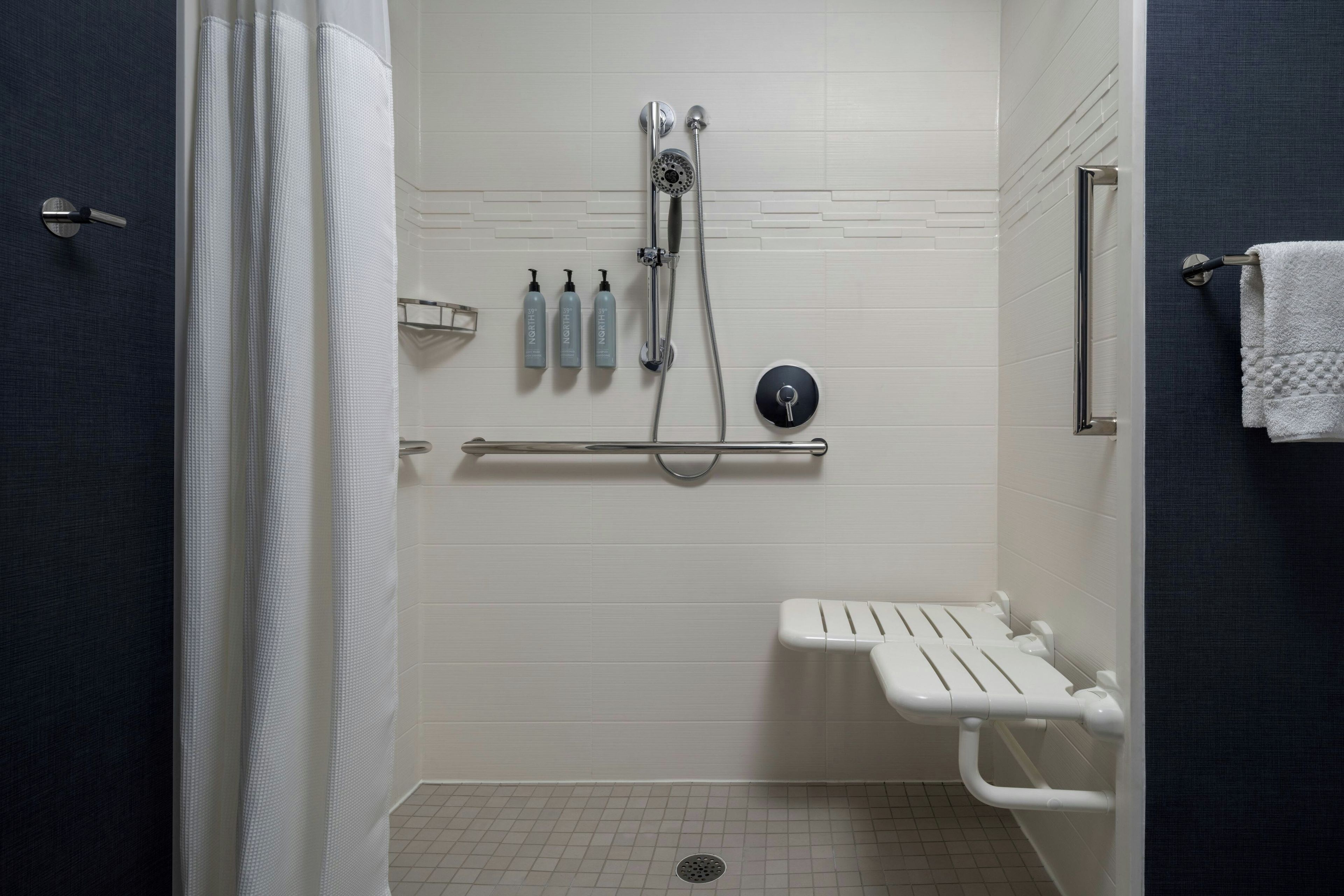 A modern bathroom with a shower, a toilet, and a towel rack.