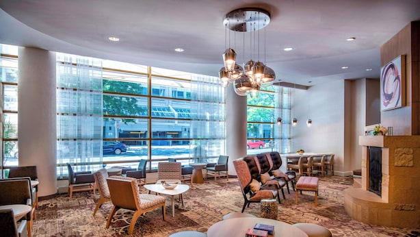 A modern lobby with seating areas, a fireplace, and large windows offering a view of the street. - Residence Inn by Marriott Washington, DC National Mall (Washington)