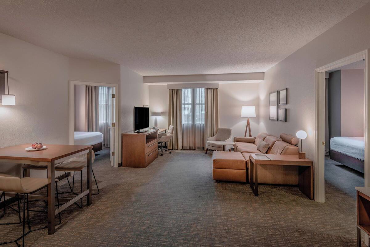 Una habitación de hotel con cama, escritorio con computadora, sofá y zona de comedor.