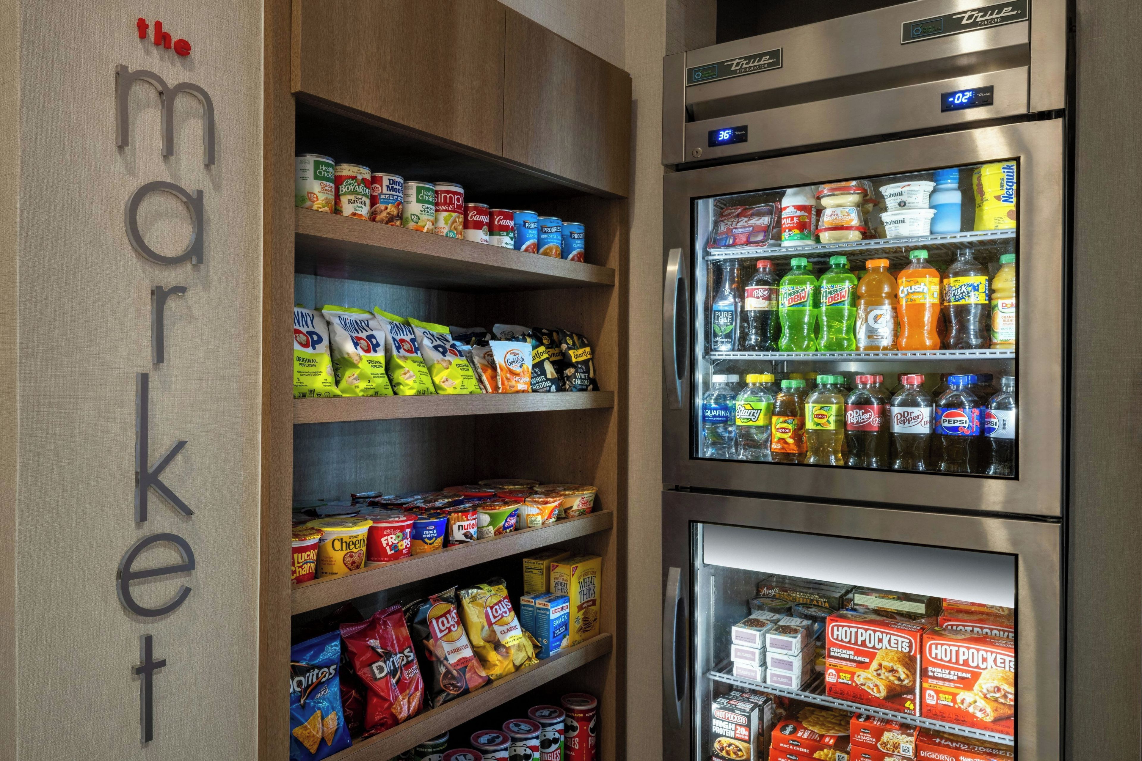 Una tienda de comestibles con estantes llenos de botanas, bebidas y productos refrigerados.