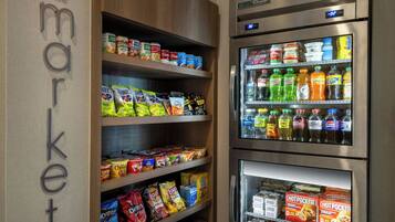 Una tienda de comestibles con estantes llenos de botanas, bebidas y productos refrigerados.