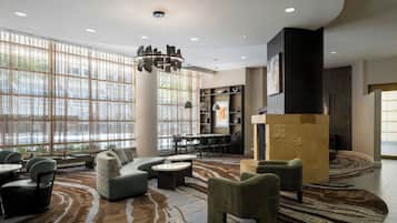 A spacious lobby with a seating area, a fireplace, and a view through large windows.