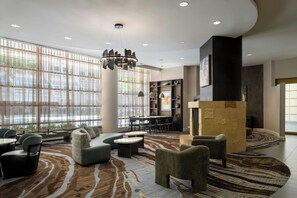 A spacious lobby with a seating area, a fireplace, and a view through large windows.