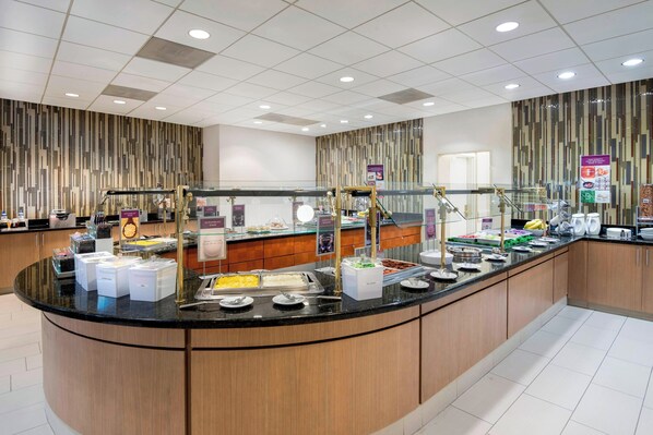 A modern breakfast bar with various food options, a glass partition, and a clean, contemporary design.