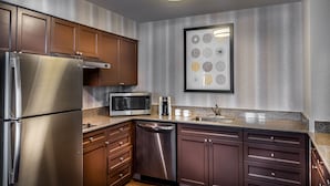 A modern kitchen with stainless steel appliances, wooden cabinets, and a granite countertop.